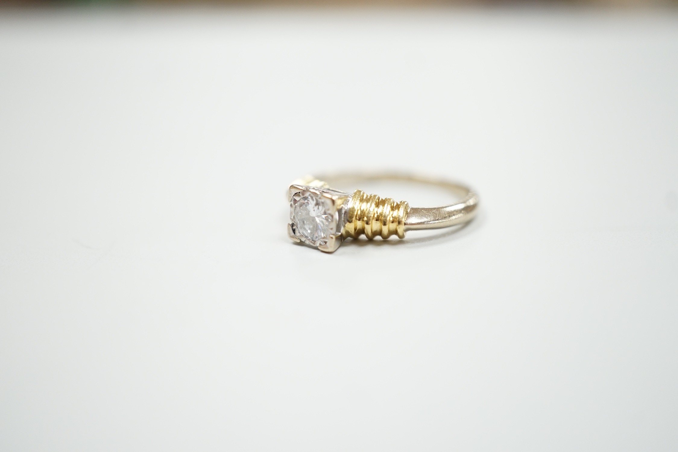 A modern 18ct two colour gold and solitaire diamond set ring, size H/I, gross weight 3.3 grams.